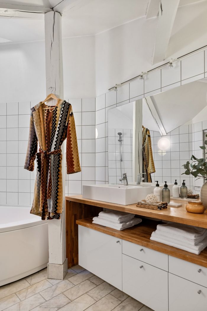 gallery-4 Contemporary bathroom with bathrobe, wooden countertop, and stylish sink design.