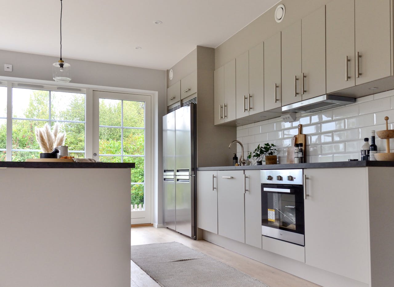 why-choose-us Minimalist white furniture and modern stainless steel appliances in stylish kitchen at home on sunny day