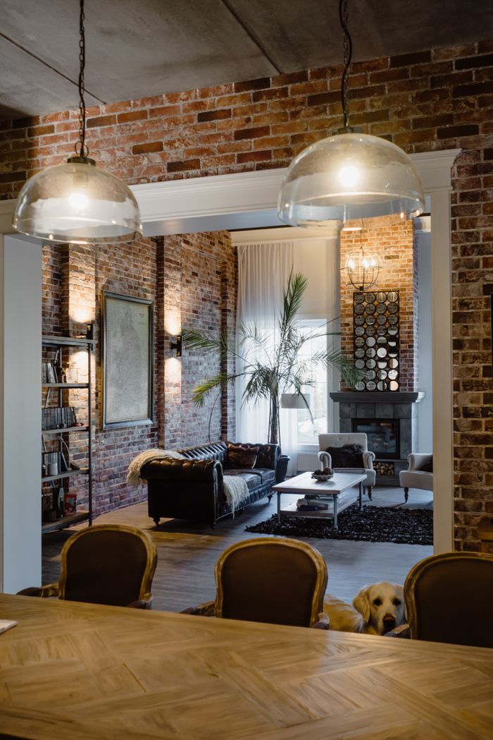 hero-img-02 A stylish modern industrial living room with exposed brick and elegant decor, featuring a cozy seating area.